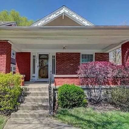 Front of a red home with white trim and a sprawling porch