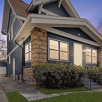 A traditional craftsman home with natural stone pillars and a glassed-in porch