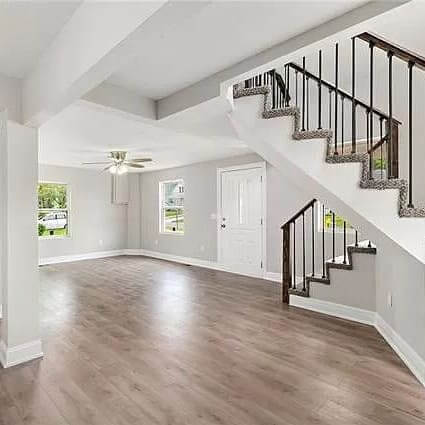 Contemporary entry room with dark hardwood floors, white walls, and an open staircase.