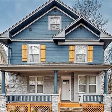 A traditional two-story home painted blue with a wide front porch